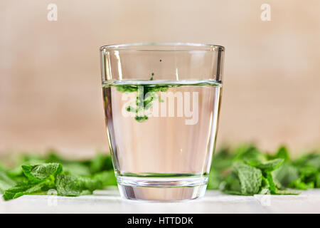 Auflösen von liquid Chlorophyll in Glas Wasser am weißen Tisch mit grüner Minze Stockfoto