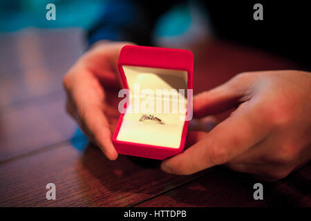 Mann macht Frau Heiratsantrag. Er eröffnete rot Schmuck Fall mit Verlobungsring. In seinen Händen hält er Feld. Stockfoto