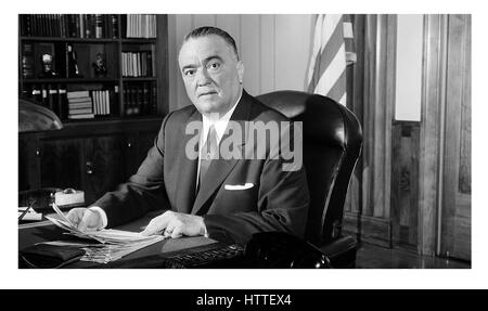 J Edgar Hoover, Porträt, Direktor des FBI in den 1960er Jahren an seinem Bürotisch mit US-Flagge hinter USA Amerika den Vereinigten Staaten von Amerika. Das J. Edgar Hoover Office ist ein flaches Bürogebäude an der 935 Pennsylvania Avenue NW in Washington, D.C. in den Vereinigten Staaten. Es ist immer noch das Hauptquartier des Federal Bureau of Investigation (FBI). Stockfoto