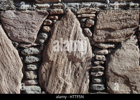 Mauer aus kleinen und großen Steinen. Hintergrund. Stockfoto