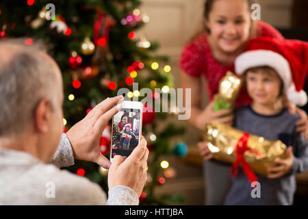 Vater die Familie Fotos auf seinem Smartphone zu Weihnachten. Stockfoto