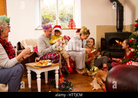 Familie Weihnachtsmorgen gemeinsam genießen. Die Kinder sind Eröffnung präsentiert mit ihren Eltern und die Großmutter beobachten. Stockfoto