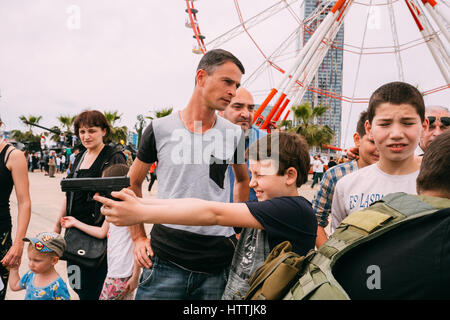 Batumi, Adscharien, Georgia - 26. Mai 2016: Boy Holding Pistole auf einer Ausstellung von Waffen während der Feier des Nationalfeiertages - die Unabhängigkeit Stockfoto