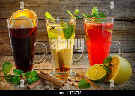 Schwarzer Tee, Milchtee, Zitronen-Tee in Tassen aus Glas auf einem Holztisch, selektiven Fokus. Schwarzer Tee mit Zitrone und Minze. Schwarzer Tee mit Zitrone, Ingwer und cinna Stockfoto