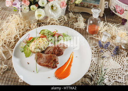 Horizontales Bild der verschiedenen Fleischsorten auf dem Board mit Schinken, Schweinefleisch, Rindfleisch, Petersilie und Oliven auf rustikalen Holz hautnah. Seitenteil des Dienens Bo im Fokus Stockfoto