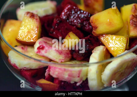 Obstsalat auf dunklem Hintergrund, Pfirsiche, Bananen, Drachenfrucht Stockfoto