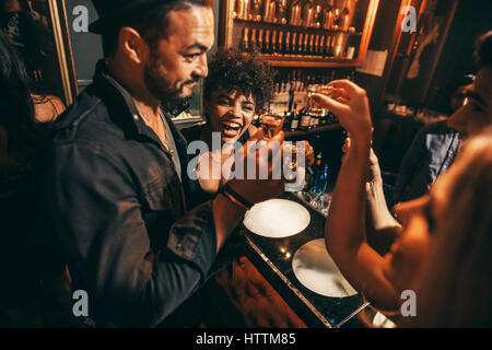 Glückliche junge Menschen Spaß mit Getränken im Nachtclub. Frauen und Männer trinken in Bar. Stockfoto