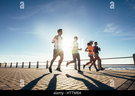 Junge Menschen, die entlang der Strandpromenade. Läufer im freien training am Meer an einem sonnigen Tag. Stockfoto