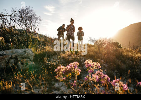 Gruppe von Jugendlichen auf Land Spaziergang an einem sonnigen Tag. Junge Männer und Frauen in Landschaft wandern. Stockfoto