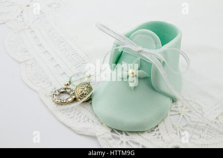 Blaue Fondant Baby Hauslatschen auf weißer Spitze Hintergrund mit Silber Charms für Feier Einladung Stockfoto