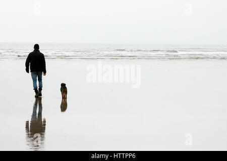 Mann und seine alten Border Terrier Hund wandern entlang dem Strand in Nord-Wales Stockfoto