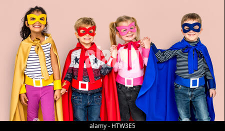 Kleine Kinder kleiden Superhelden an den Händen halten Stockfoto