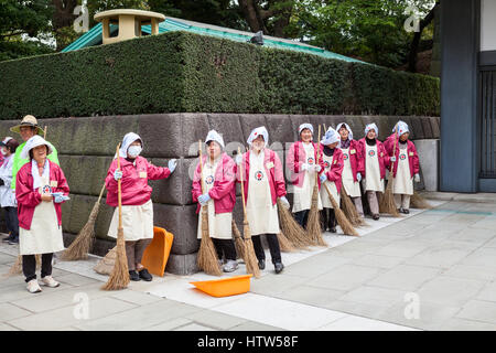 TOKYO, JAPAN - ca. April 2013: Reinigung Arbeitnehmerinnen mit Besen in rosa Jacken sind auf den inneren Bereich der Kaiserpalast von Tokio auf der Kyuden Tote Stockfoto