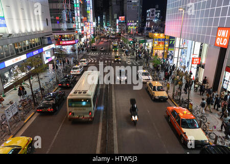 TOKYO, JAPAN - ca. April 2013: Kreuzung mit Fahrzeugen liegt in der Innenstadt. Beleuchtete Werbung Banner sind an Gebäudefassaden. Das Nachtleben ist auf dem s Stockfoto
