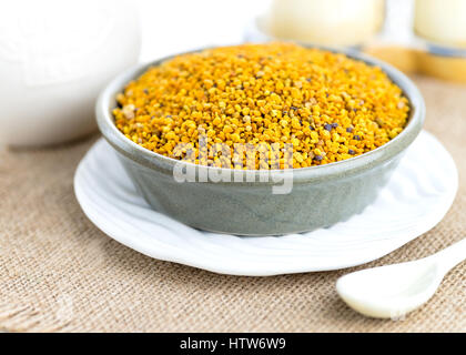 volle Teller von Bienen Pollen erschossen in einem selektiven Fokus kontrastierende Texturen in Tuch und Whit Keramik-Keramik im Hintergrund Stockfoto