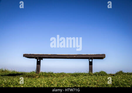 Bank auf dem grünen Rasen mit Sitzbank mit klaren, blauen Himmelshintergrund Stockfoto