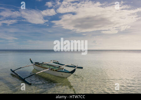 Traditionelle Filipino Fischerboot mit Möwen auf die Ausleger in einem ruhigen Meer schweben. Stockfoto