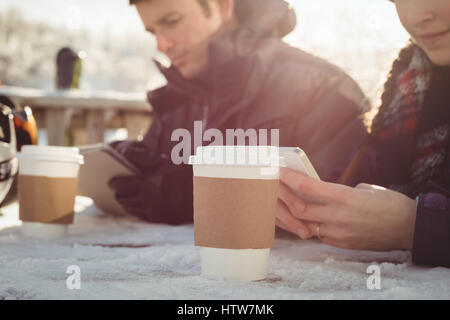 Skifahrer-paar mit Handy und digitale Tablett am Tisch Stockfoto