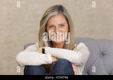 Frau mittleren Alters sitzen auf einer couch Stockfoto