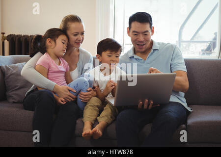 Eltern und Kinder mit Laptop im Wohnzimmer Stockfoto