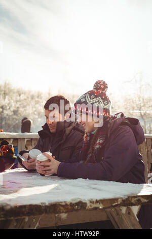 Glücklich Skifahrer paar mit Handy und digitale Tablett am Tisch Stockfoto