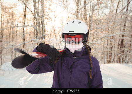 Frau in Skibekleidung Ski auf ihrer Schulter hält Stockfoto