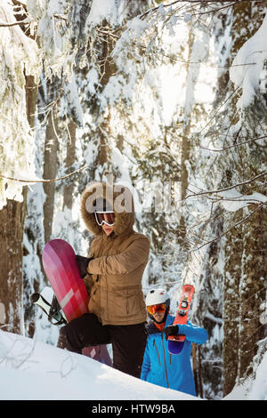 Paar mit Ski und Snowboard zu Fuß auf verschneiten Bergen Stockfoto