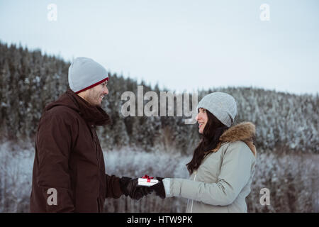 Frau mit Geschenk an den Menschen auf Schnee Berg bedeckt Stockfoto