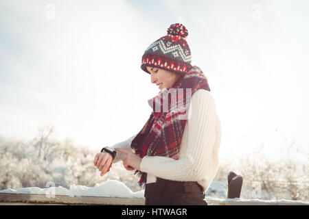 Frau in Winterkleidung Überprüfung ihrer smartwatch Stockfoto