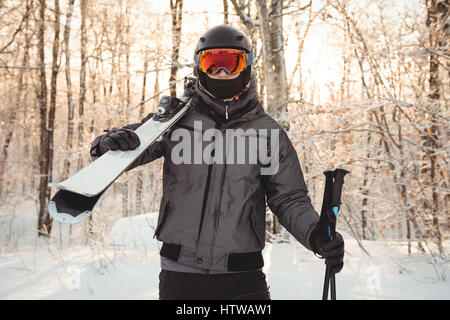 Mann in Skibekleidung Ski auf ihrer Schulter hält Stockfoto