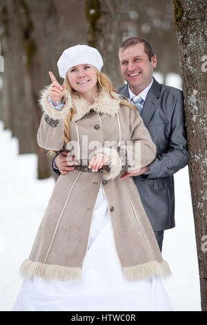 Braut mit Finger für den Bräutigam. Brautpaar ist im verschneiten Winterpark Stockfoto