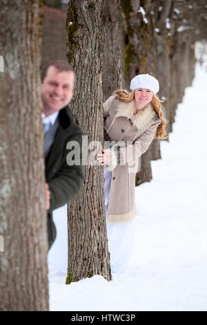 Braut-Kollegen, vom Baum hinter Bräutigam in Winter Park, Brautpaar zu Fuß Stockfoto