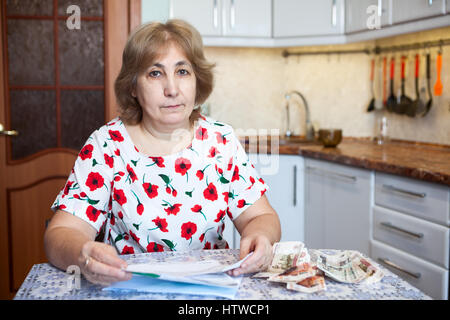Portrait von kaukasischen Frau mit Bargeld und Quittungen für kommunale Zahlung auf Tisch Stockfoto