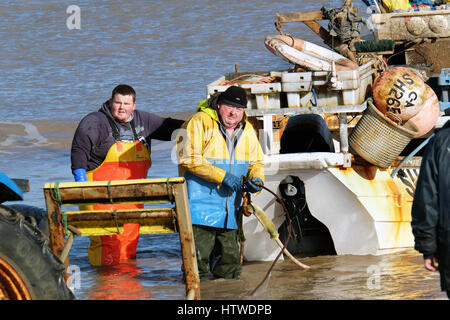 Kleine Schale Fischerboot mit zwei Mann Besatzung zurück zum Strand am Hornsea in Yorkshire, England. Stockfoto