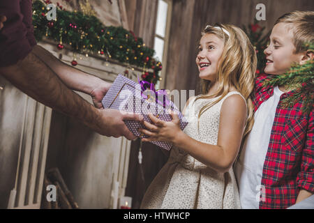 Niedliche kleine Mädchen Weihnachtsgeschenk von ihrem Vater erhalten Stockfoto