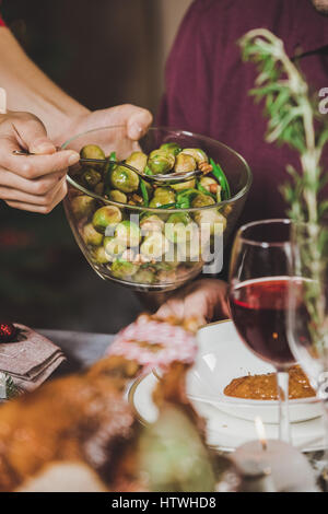 Teilansicht von Frau weglegen Brussel sprouts auf Teller Stockfoto