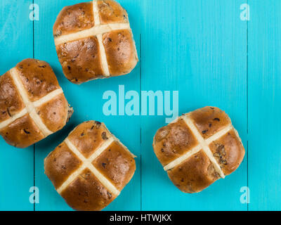 Vier Hot Cross Buns Kulinarische Ostern vor einem blauen Hintergrund Stockfoto