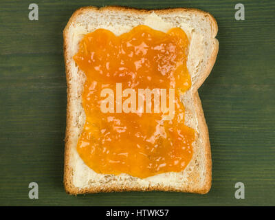 Buttertoast mit Marillenmarmelade vor einem grünen Hintergrund Stockfoto