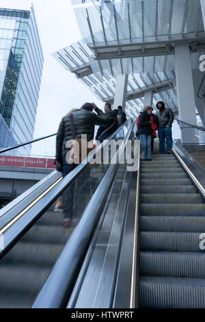 Reisende, die eine Rolltreppe hinauf in modernen Gebäude im Freien in London Stockfoto