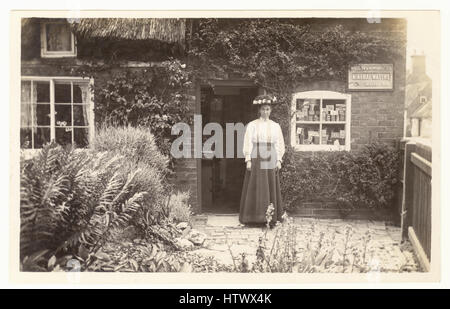 Originale edwardianische nostalgische Postkarte der Ladeninhaberin, Einzelhändlerin, vor ihrem ländlichen Dorfladen, Waren im Fenster, zu ihrem Haus, möglicherweise Newark in Trent, Nottinghamshire Edwardianerin. Edwardianerin. Edwardianisches Geschäft. Großbritannien um 1905 Stockfoto