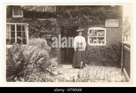 Ursprüngliche edwardianische nostalgische Postkarte der Ladenbesitzerin, Einzelhändlerin, außerhalb ihres ländlichen Dorfladens, Waren im Fenster, bei ihr zu Hause, möglicherweise Newark on Trent, Nottinghamshire U.K. um 1905 Stockfoto