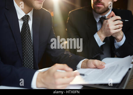 Closeup Portrait zweier unkenntlich erfolgreiche Geschäftspartner tragen schwarze formelle Anzüge Dokumentation überprüfen und diskutieren-Deal bei Tisch du Stockfoto