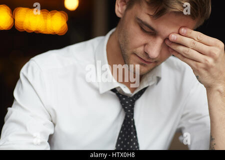 Porträt von müde junger Geschäftsmann in Hemd und Krawatte reiben schloss die Augen während der Arbeit spät in die Nacht Stockfoto