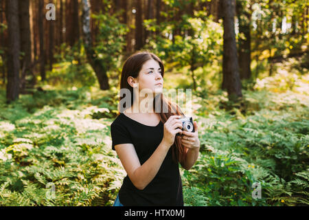 Fröhliches Rothaarige kaukasische Mädchen fotografieren junge Frau Fotografen die alte Retro Vintage Filmkamera im Sommer grünen Wald. Mädchen, gekleidet In ein B Stockfoto