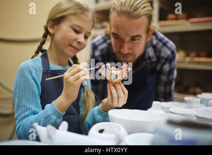 Niedliche Mädchen malen Ton Spielzeug und Figuren mit ihrem Vater in der Nähe von Stockfoto
