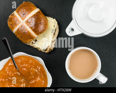 Getoastet Hot Cross Brötchen mit Kaffee und Aprikosenmarmelade vor einem schwarzen Hintergrund mit Keine Personen Stockfoto