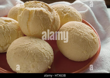 Closeup auf einem köstlichen brasilianischen Käsebrot (Pao de Queijo) serviert in rote Platte, auf weißen Geschirrtuch Stockfoto