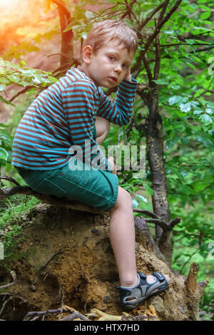 Kleiner Junge im gestreiften Pullover und Shorts im Sommer Waldpark im Sonnenlicht Stockfoto