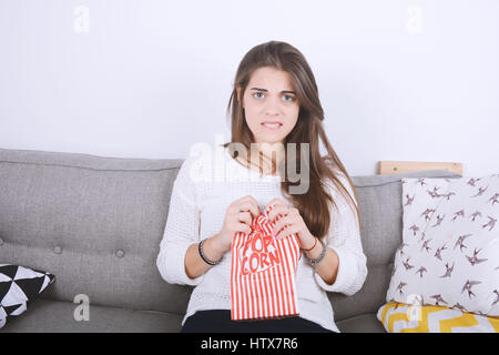 Junge Frau Essen Popcorn und Filme entspannt auf der Couch. Im Innenbereich. Stockfoto