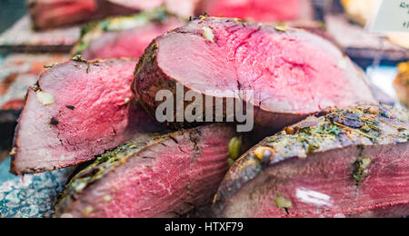 Rohe rosa gebratenes Rindfleisch Stücke auf dem Display im Markt mit Knoblauch und Kräutern Stockfoto